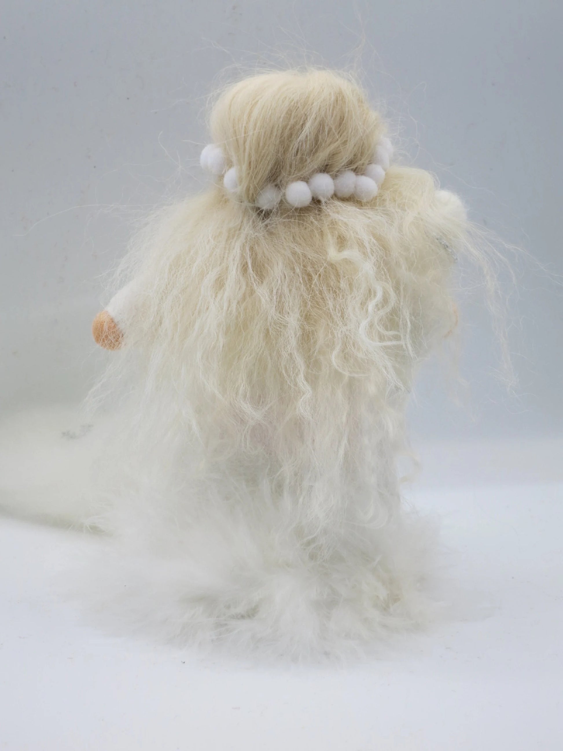 Rückansicht der Winterfigur mit sehr langem lockigem Blondhaar, weißem Schneeball-Kranz und weichem Filzgewand