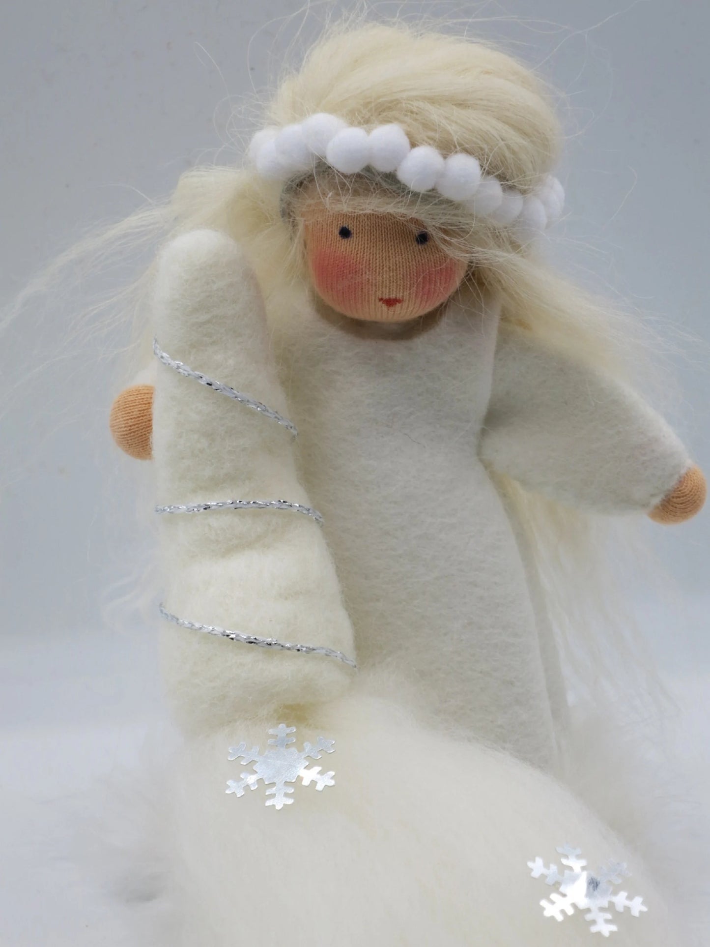 Detail der handgefertigten Winterfigur mit weißem Filz, silberner Borte, Schneeflocken und blondem Wollhaar