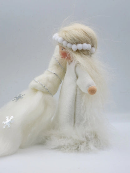 Seitliche Ansicht des Winter-Blumenkinds mit weißem Filzkleid, langem Wollhaar und Schneeteppich mit silbernen Flocken