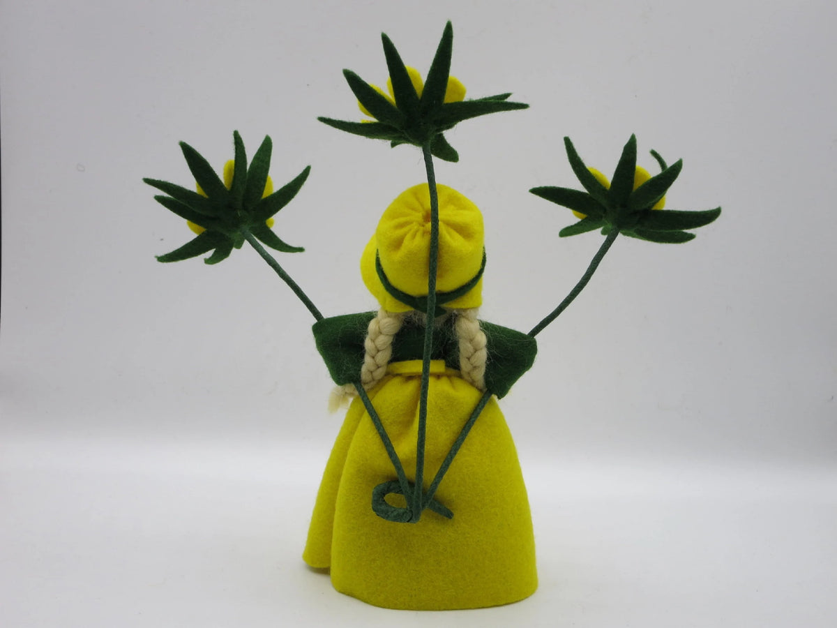 Rückansicht des Winterling-Blumenkinds mit blondem Zopf und gelber Blütenmütze