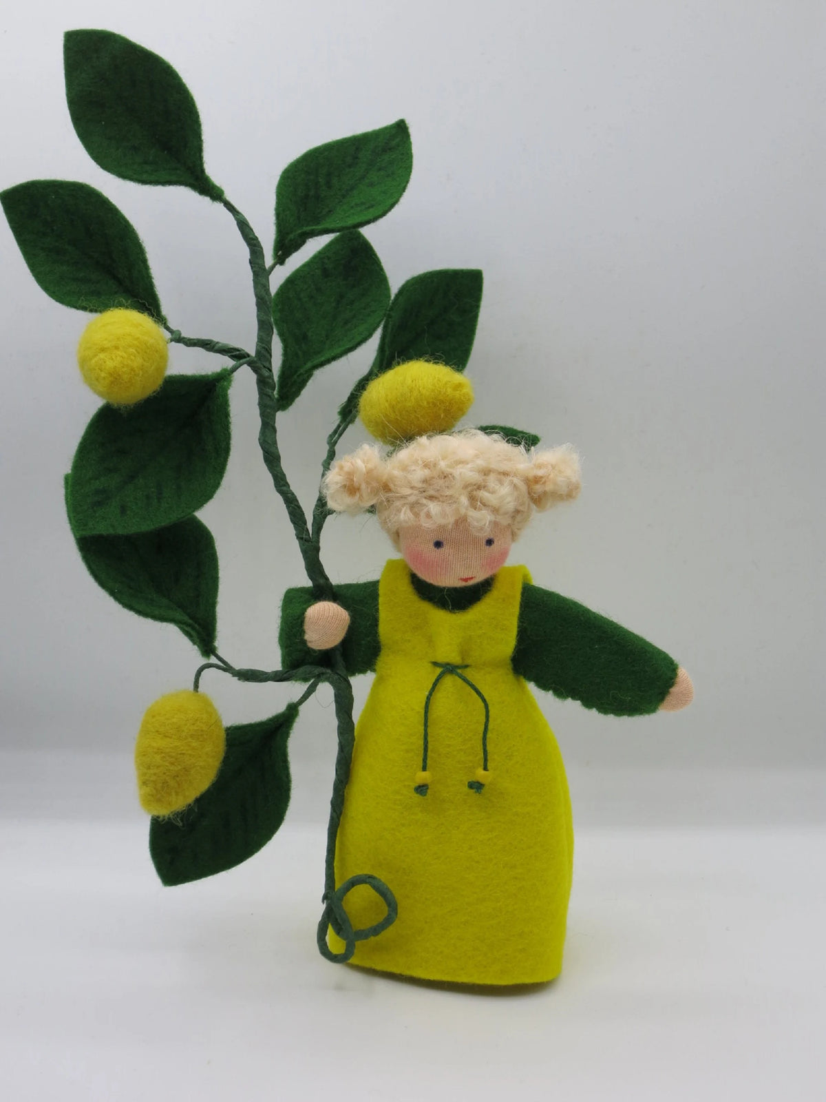 Zitronen-Blumenkind aus Wollfilz von schräg vorn, gelbes Trägerkleid über grünen Ärmeln, Figur für den Sommer-Jahreszeitentisch.