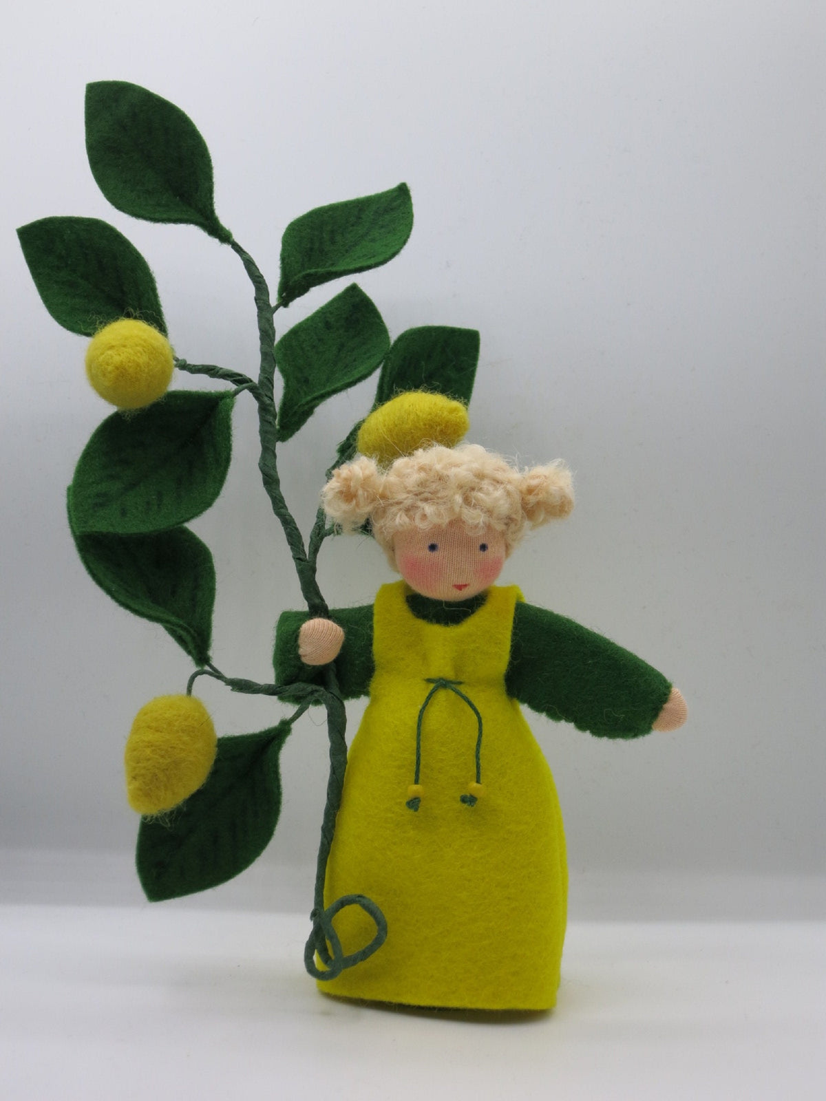 Zitronen-Mädchen als Blumenkind aus Wollfilz mit drei gefilzten Zitronen am Zweig und gelbem Trägerkleid, Figur für den Waldorf Jahreszeitentisch im Sommer.